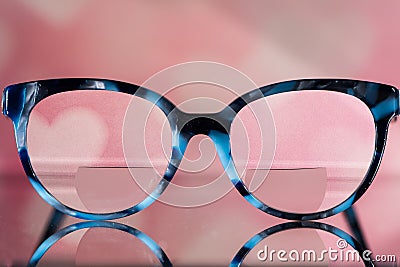 Eyeglasses Glasses with Bifocals and Black and blue Frame smudged view agaist a blurry pink background with white hearts. Blurry Stock Photo