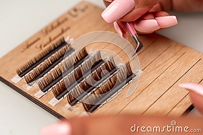 Eyelash extensions, lashmaker tools. Artificial eyelashes on a white tablet and pink silicone brush comb, close up. Stock Photo
