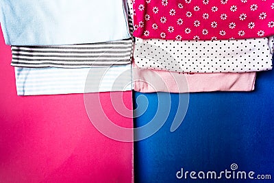 Fabric Sewing. Folded blue and pink bodysuit on minimalistic pink and blue background. diaper for newborn boy and girl. Stack of i Stock Photo