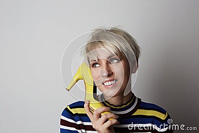 Fabulous girl female short hair blonde using yellow heels like phone in studio. Fashion people and glamour concept. Stock Photo
