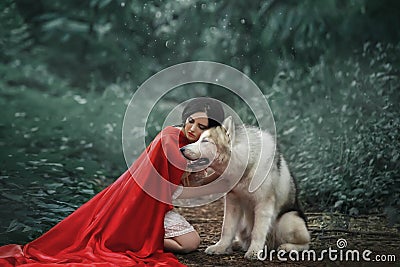 Fabulous image, dark-haired brunette attractive lady in short white dress, long red scarlet cloak lying on ground sits Stock Photo