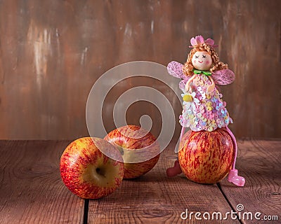 Fabulous postcard. Scatter red apples and an apple fairy in a pink dress sitting on an apple Stock Photo