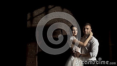 Fabulous wedding couple standing against black wall with the shadow from the metal gate. Action. Portrait of young bride Stock Photo
