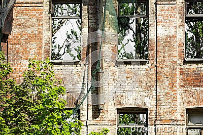 Facade abandoned brick building overgrown with grass and trees Stock Photo