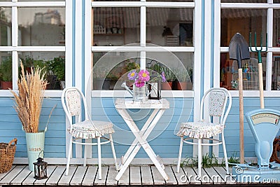 Facade blue Cozy home with a beautiful garden in summer. Beautiful farmhouse with wicker baskets and green plants on terrace. Whit Stock Photo