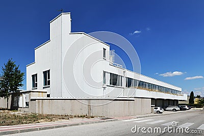 Facade of a lonely industrial building with white cladding, many windows and a clear blue sky Stock Photo