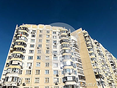 The facade of a modern residential multi-storey building against a clear blue sky. The concept of residential real estate Stock Photo