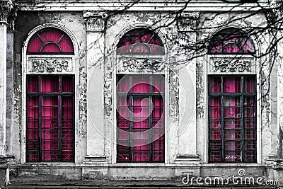 Facade of old abandoned building with three large arched windows of pink glass. Monochrome background Stock Photo
