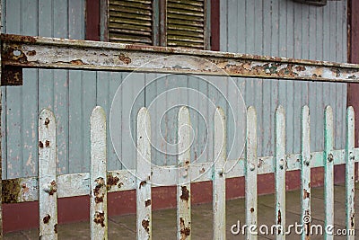 Facade of old abandoned house with rusty metal fence and grungy weathered green wood wall Stock Photo