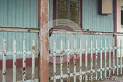Facade of old abandoned house with rusty metal fence and grungy weathered green wood wall Stock Photo