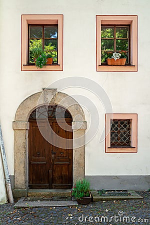 The facade of an old building with a wooden door and three windows. Stock Photo