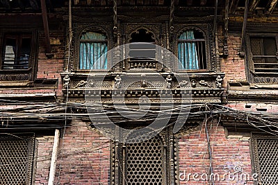Facade of an old dusty building in Kathmandu decorated with Newari wood carving Stock Photo