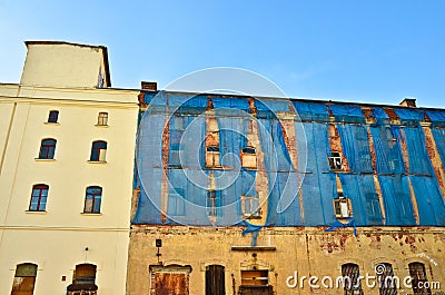 The facade of an old ruinous building is mantled with some blue curtains to protect the pedestrians Stock Photo