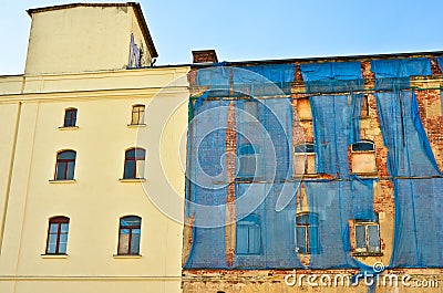 The facade of an old ruinous building is mantled with some blue curtains to protect the pedestrians Stock Photo