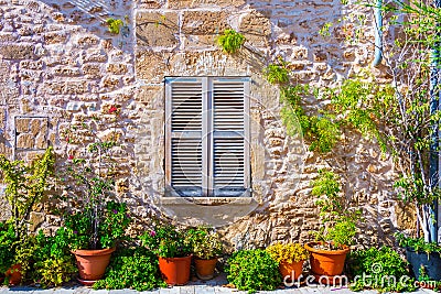 The facade of an old stone house with wooden brown shutter and flowerpots Stock Photo