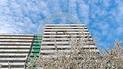 Facade with rows of white, concrete balconys and green structure of building. Stock Photo