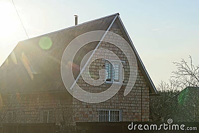 Facade of a rural brown house made of bricks with one window under a gray slate roof Stock Photo
