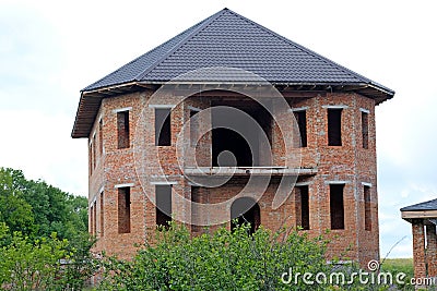 Facade of an unfinished two-story house with no red brick windows. Stock Photo