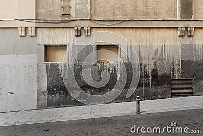 Facade of a very old building with granite ashlars, windows blocked with brick and cement and renovated stone floors Stock Photo