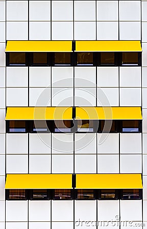 Facade with white tiles and yellow awnings Stock Photo