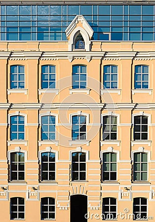 The facade of the yellow building with glass Windows and an attic floor Stock Photo