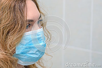 The face of an adult red-haired woman in a medical mask. Protection from COVID-19, flu, SARS, allergies, viruses. Stock Photo