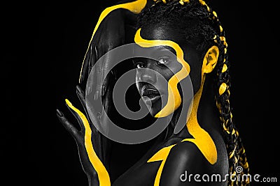 Yellow and black body paint. Woman with face art. Young girl with colorful bodypaint. An amazing afro american model Stock Photo