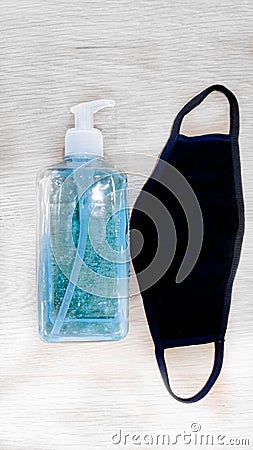 Face black masks and hand sanitizer bottle on table for peple washing hands to help stop spreading outbreak coronavirus Stock Photo
