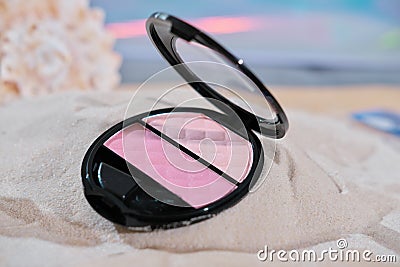 face blush on a sandy beach. summer waterproof cosmetics. pink shades of cosmetic for face, Stock Photo