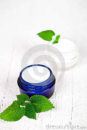 Face cream in jars with urtica leaves Stock Photo