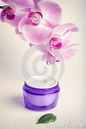 Face/hand cream jar and purple orchid flowers, vertical shot Stock Photo