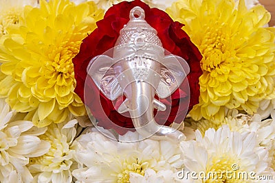 Face of lord Ganesha placed over beautiful rose and chrysanthemum flowers. Use for religious concepts Stock Photo