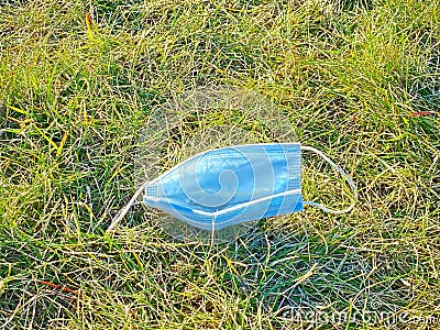 A face mask dumped on a field. Concept: Waste garbage during covid 19, coronavirus Editorial Stock Photo