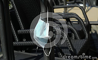 Face mask hanging on stacked chairs in a closed restaurant, food and drink business corona lockdown Stock Photo