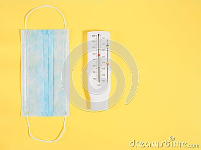 Face mask for protection against viruses and a medical device peak flow meter for measuring lung volume on yellow background Stock Photo