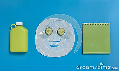 Face mask , reusable nwater bottle, cucumber, notepad on blue background. Dehydration. Stock Photo