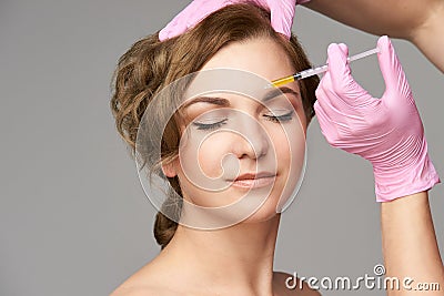 Face needle injection. Young woman cosmetology procedure. Doctor gloves. Brow between Stock Photo