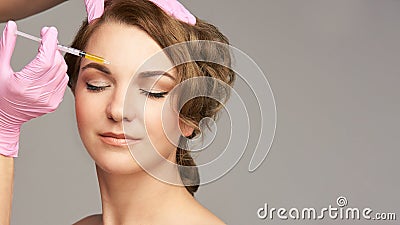 Face needle injection. Young woman cosmetology procedure. Doctor pink gloves. Brow Stock Photo