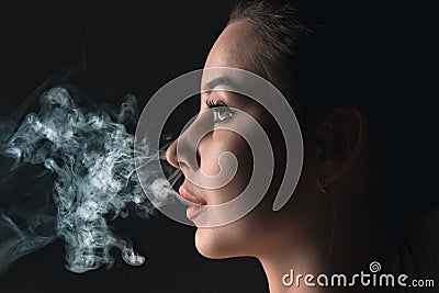 The face of vaping young woman at black studio Stock Photo