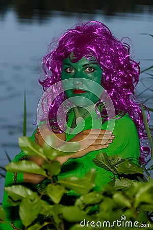 The face of a woman in the form of a water witch amidst the green at dusk. Stock Photo