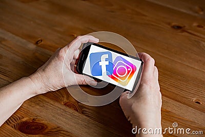 Facebook and instagram logo sign application screen on mobile phone online retail service, hands on Editorial Stock Photo