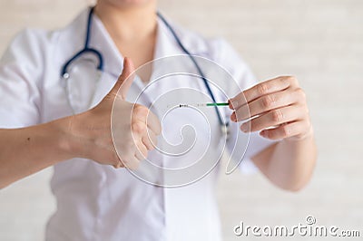 A faceless doctor in a medical coat and with a stethoscope holds a positive pregnancy test. The gynecologist shows a Stock Photo