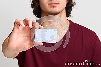 Faceless male stretches hand with blank card for your advertisement or promotion text, poses at white background, man wearing Stock Photo