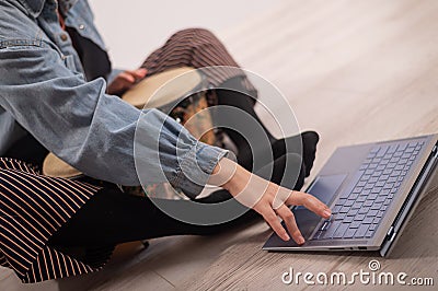 A faceless woman sits on the floor at home and watches educational videos of playing mini bongs. Girl remotely learns to Stock Photo