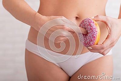 A faceless woman in white panties holds a pink donut imitating sex. A hint of a gesture of sexual intercourse Stock Photo