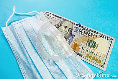 Facemask on banknote of 100 dollars on blue background. Medical mask price increase concept, protect against coronavirus Stock Photo