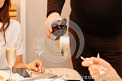 Without faces. a man pours champagne into women& x27;s glasses. Stock Photo