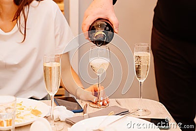 Without faces. a man pours champagne into women& x27;s glasses. Stock Photo