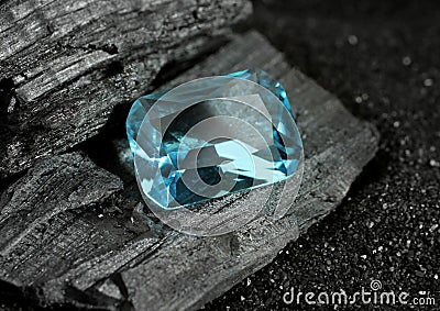 Faceted blue jewelry gemstone aquamarine on black coal background Stock Photo