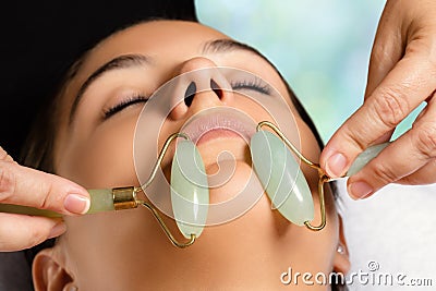 Facial beauty treatment with jade rollers. Stock Photo